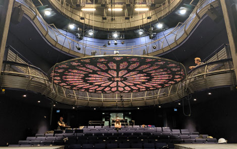 the inside of the Richard Burton theatre, transformed into Notre Dame with a huge circular stained glass window lowered from the ceiling 