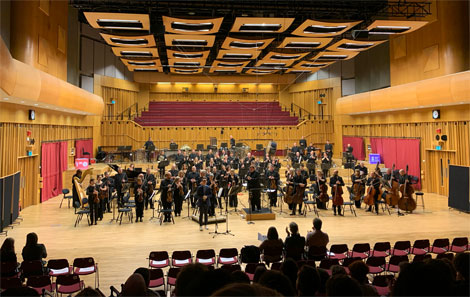 The orchestra stand up after their performance of Night Music at Hoddinott Hall, Cardiff, congratulated by Jasper and colleagues in the front seats 