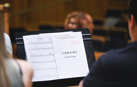 a close up of the score of Chrome by Errollyn Wallen on the stand of an RWCMD music student. Errollyn is in the background 