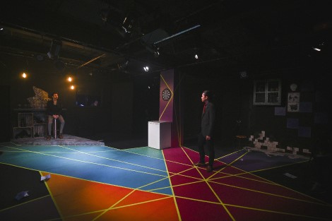 the set for Human Animals shows an actor standing on a floor with a geometric pattern on it 