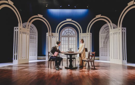 A very dignified set for 'Arcadia' with Georgian type arched windows creating a lounge with the two actors are sitting a a table 