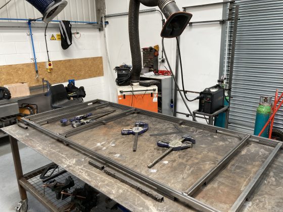 The workshop at Llanishen with metal frames on a metal table, ready to be welded into place 