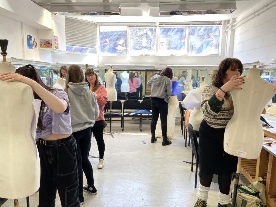 students working on their costume designs with a row of mannequins lining the room 