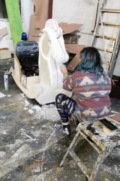 Millie has her back to us, painting a white rocking horse 